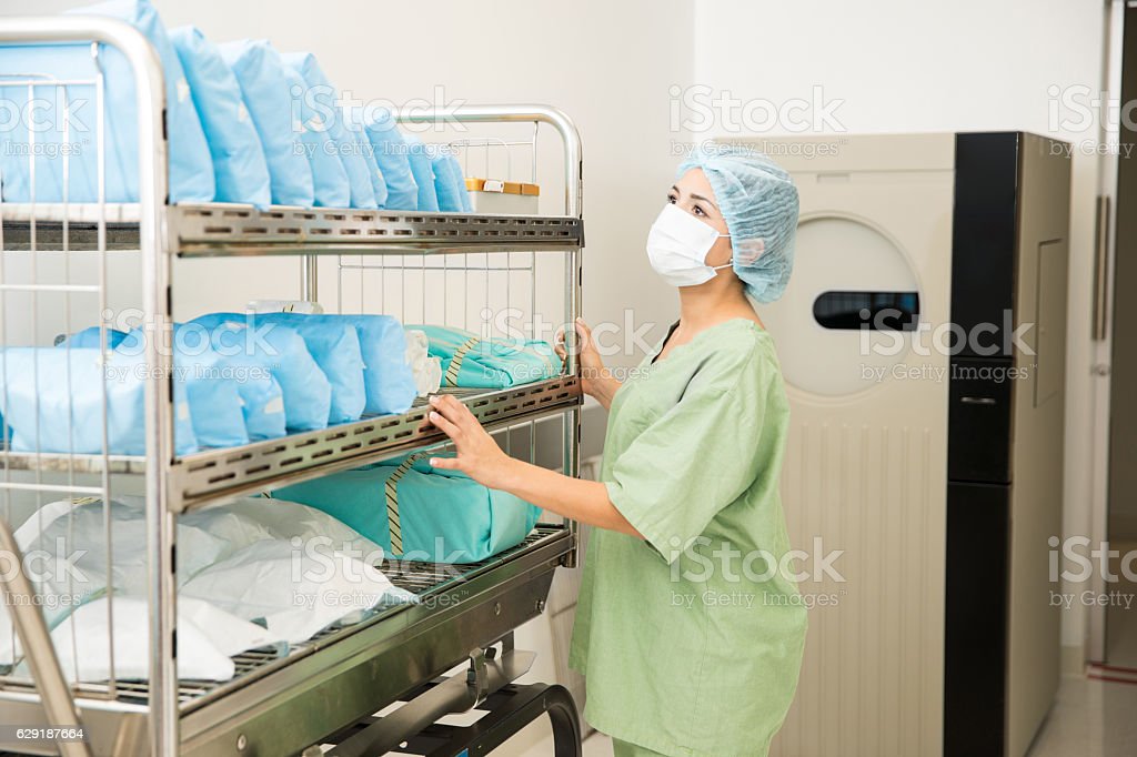 Cute young woman in scrubs looking at a cart full of clean and sterile clothing in a hospital